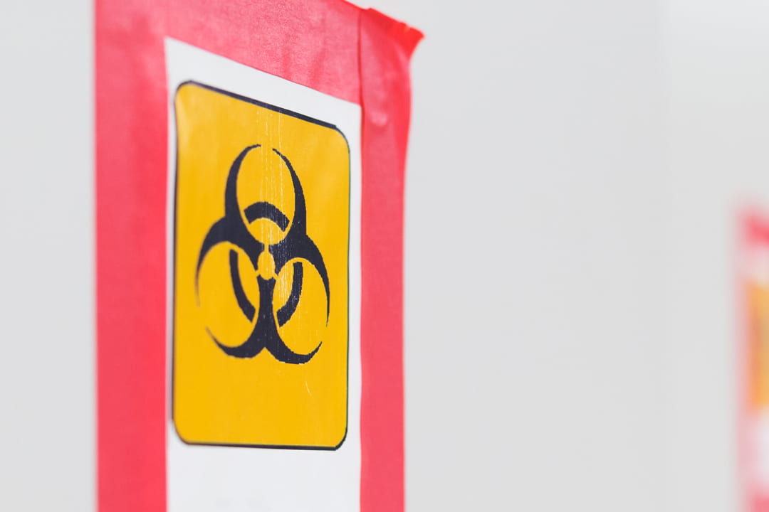 Printed yellow biohazard symbol attached to a wall with red tape. 